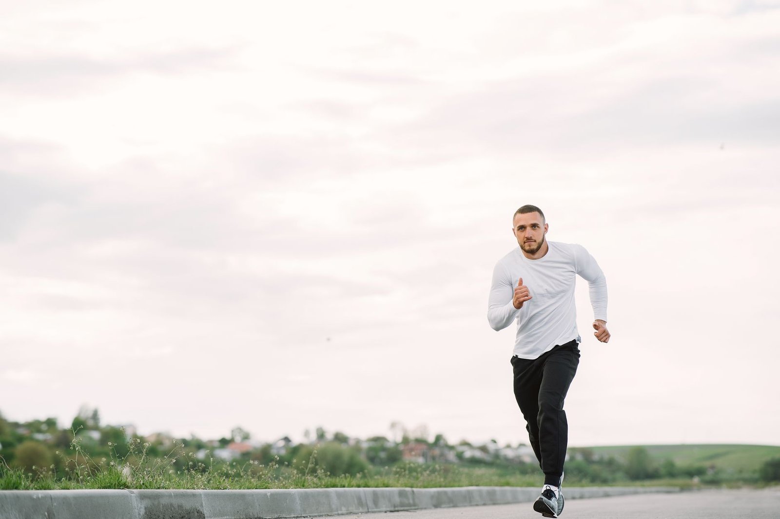 Adult man running on an empty road in casual sportswear, showcasing fitness and healthy lifestyle.
