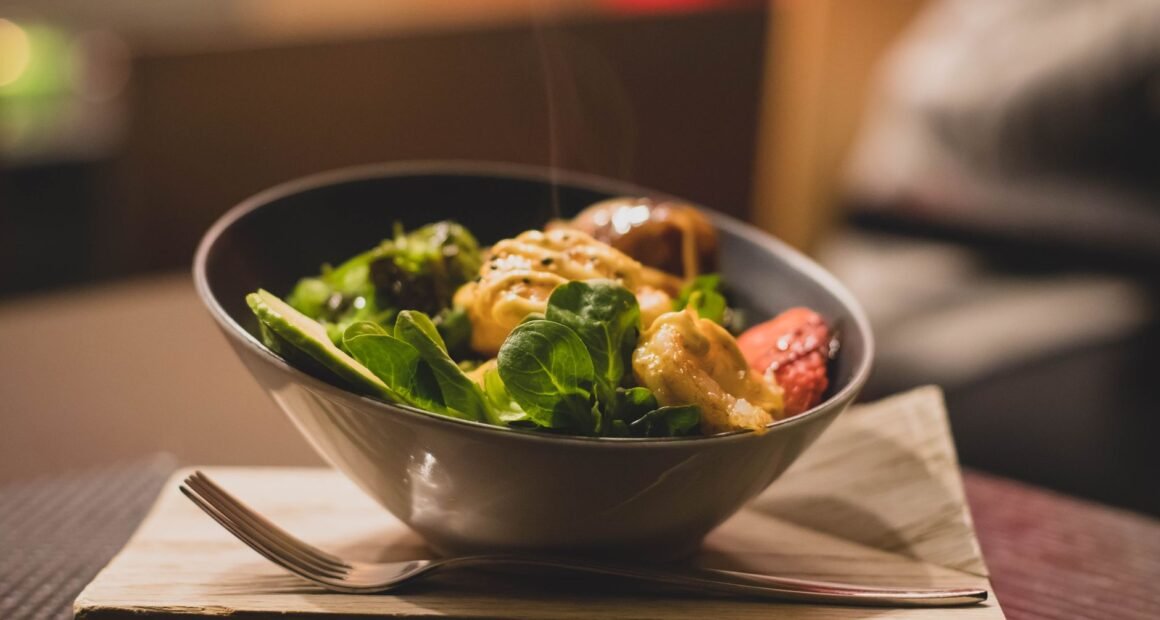 Delicious bowl of salad with fresh greens and grilled chicken served on a wooden platter.