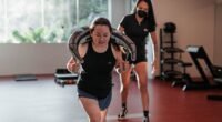 Two women focused on strength training in a Singapore gym with a personal trainer.