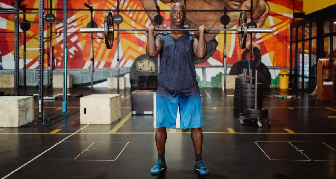 Muscular man lifting barbell in a colorful gym, exuding strength and fitness.