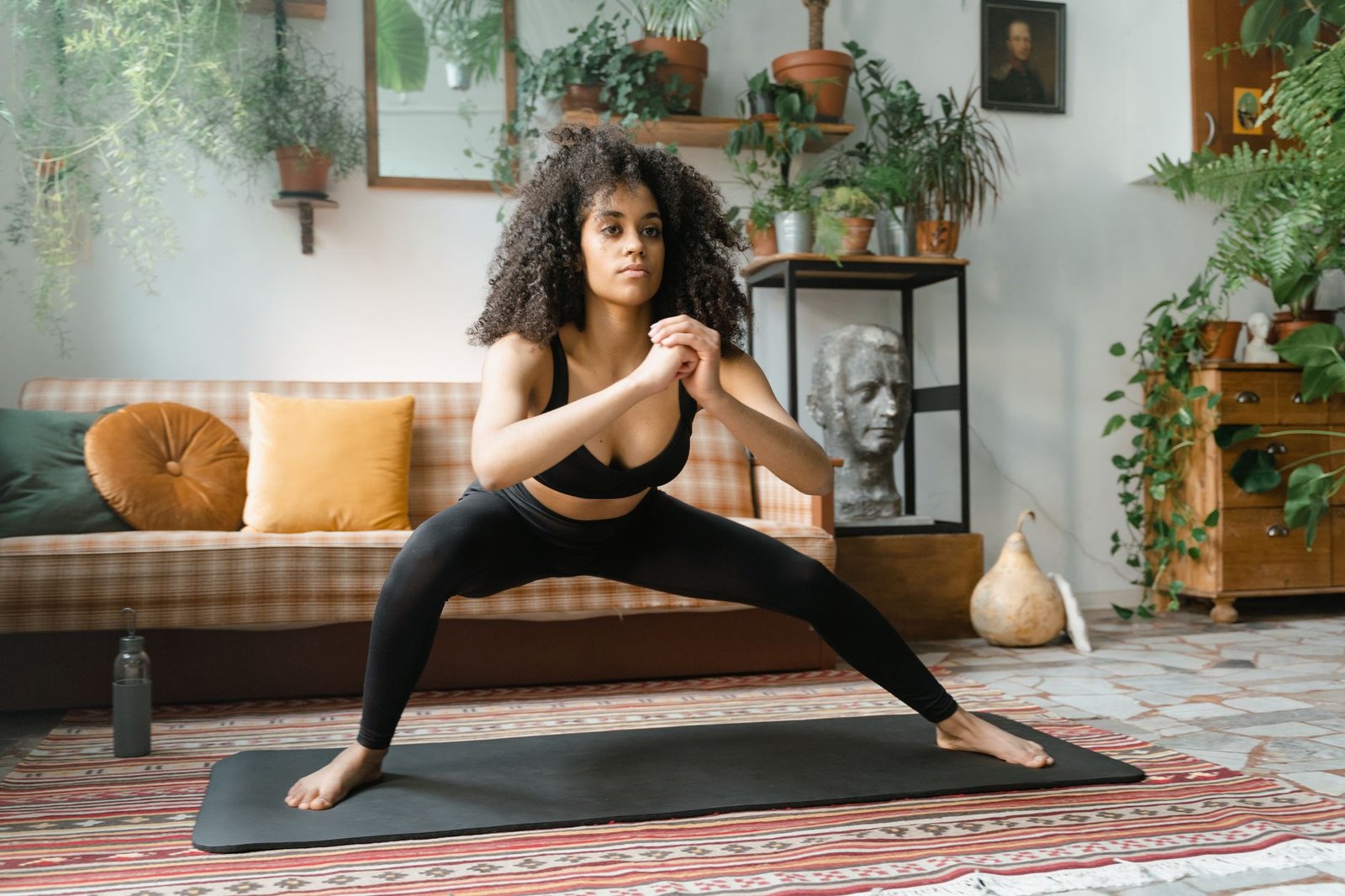 A woman exercises on a yoga mat surrounded by indoor plants, capturing a healthy lifestyle.