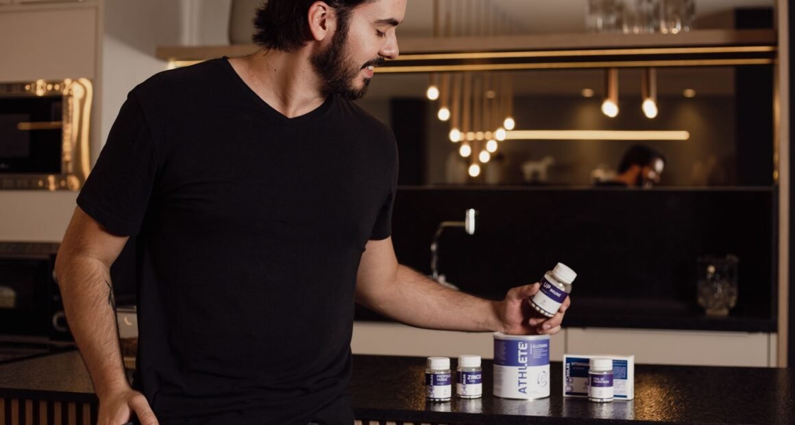 A man examines supplement bottles on a modern kitchen counter, reflecting a healthy lifestyle.